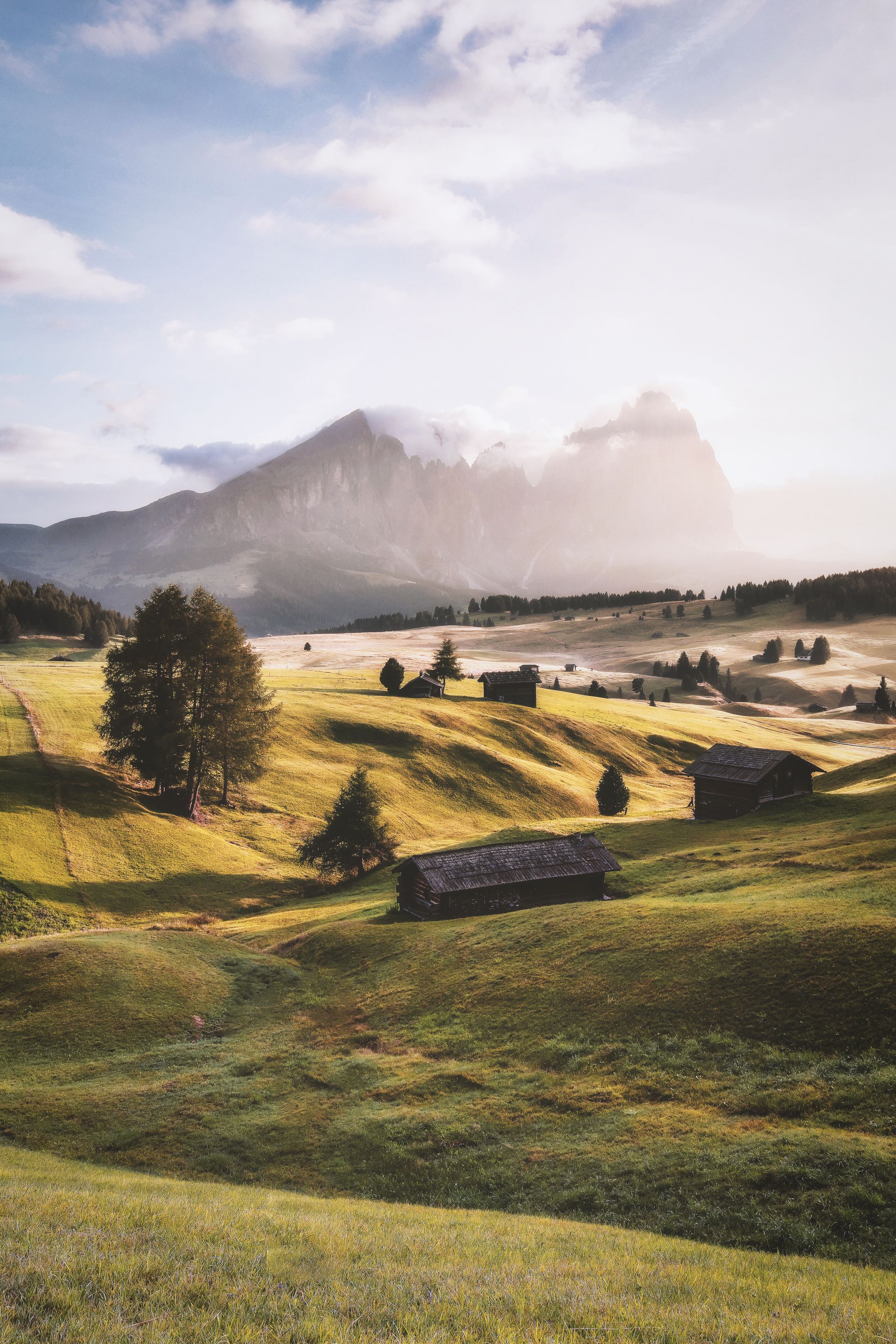 Almwiese mit Berghütten vor einer Tiroler Bergkulisse im Morgenlicht